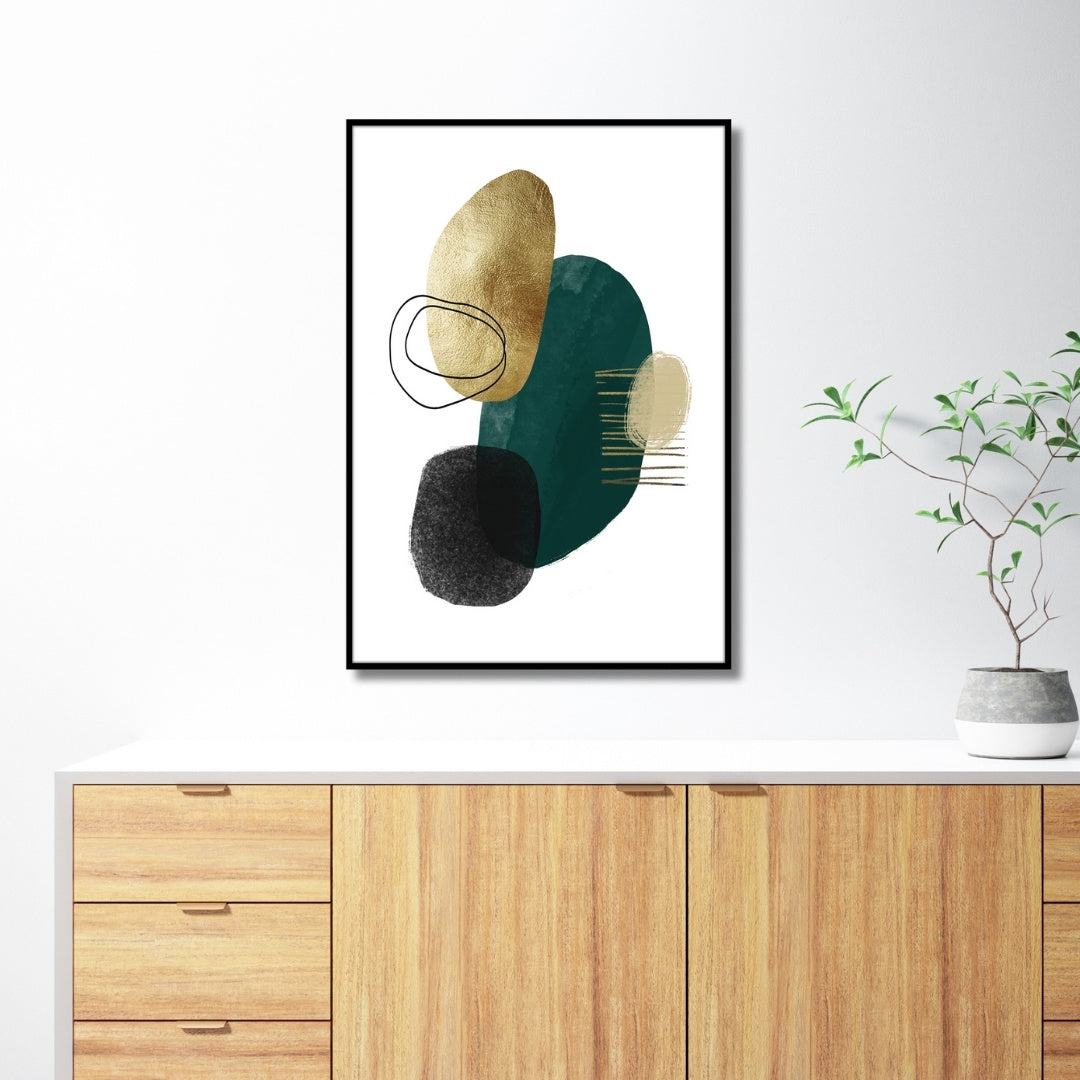 Das Rahmenbild in den Maßen 50x70cm zeigt ein abstraktes Bild im minimalistischen und klaren Design. Das Bild zeigt ungleichmäßige runde Formen und Linien in den Farben Gold, Beige, Dunkelgrün und schwarz. Die Formen sind auf weißem Hintergrung gedruckt.