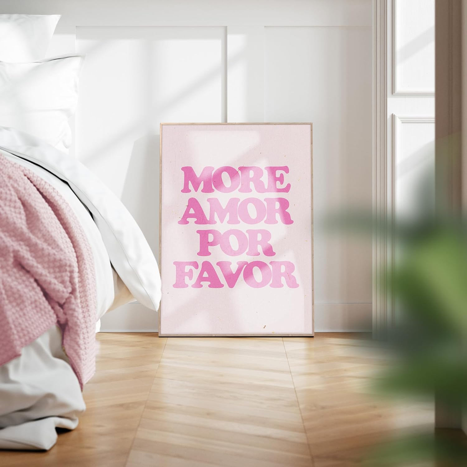 Das gerahmte Bild in den Maßen 50x70cm ist sehr modern und minimalistisch. Der Untergrund ist beige und es ist der Schriftzug " More Amor por Favor" in kräftigem Rosa und in moderner Schrift abgebildet. Die Typografie füllt das Rahmenbild aus.